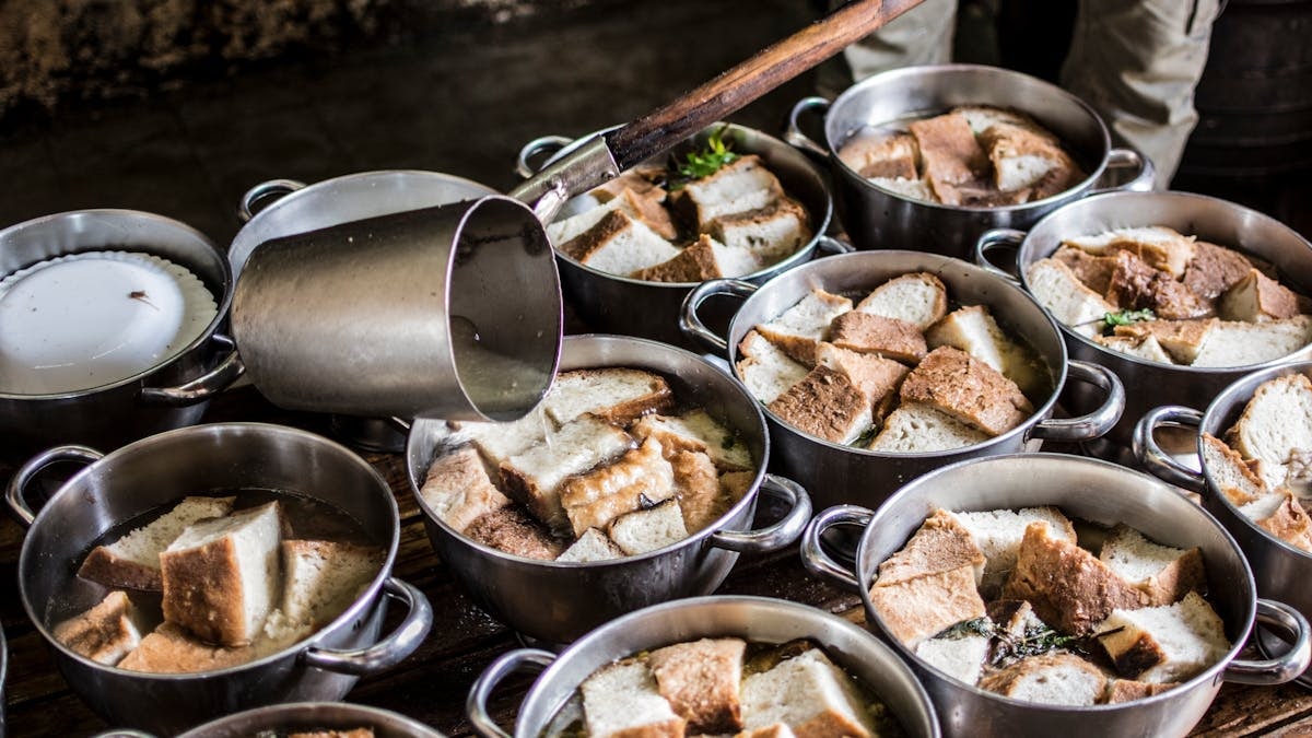A rustic kitchen scene with pots of traditional bread soup being prepared in the Azores.